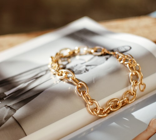 Chunky gold chain-link bracelet styled on an open magazine